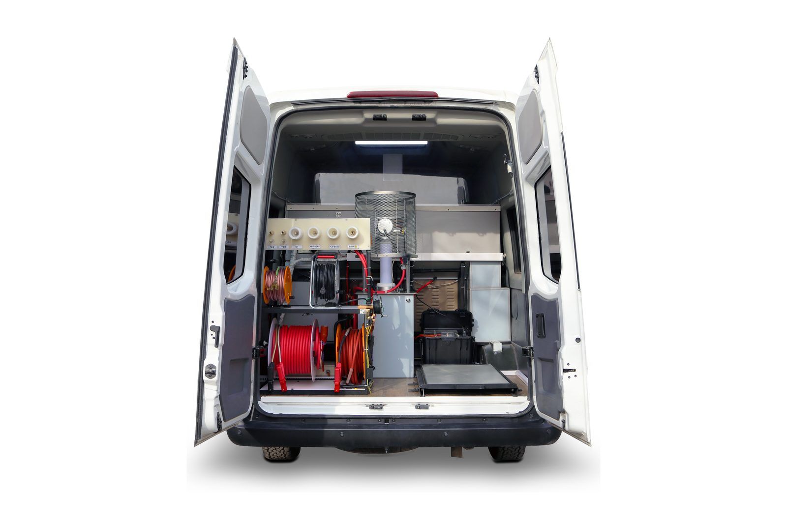 The van from behind with both rear doors open: a connection panel with six terminals, cable reels in red and orange, a unit inside a mesh guard, and black instrument cases.
